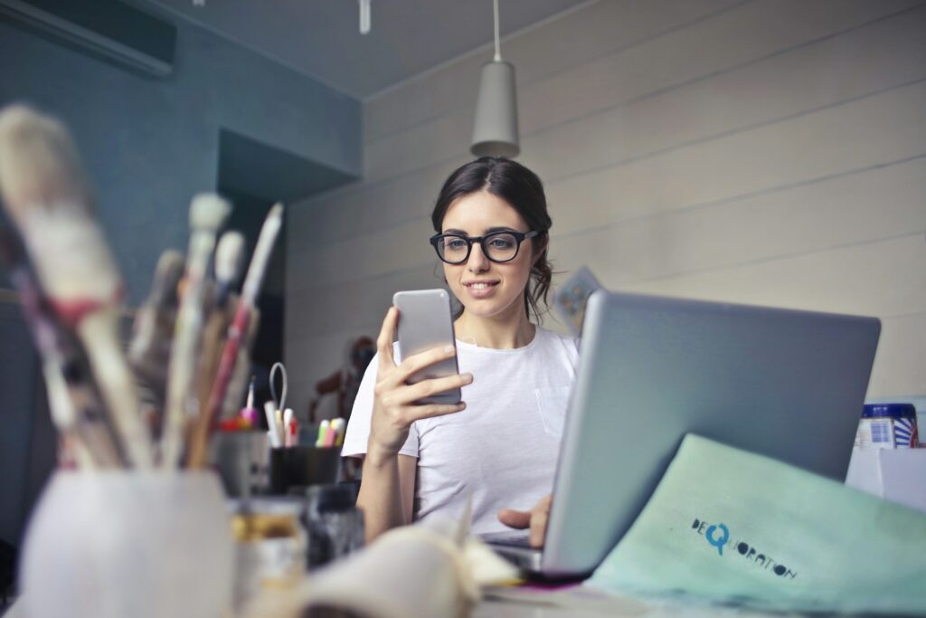 A business owner checking social media on her phone at her desk